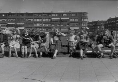 Een groep kinderen zit op een hek op de Noorderhavenkade,1955.