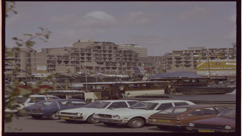 De Leuvehaven met binnenvaartschepen en geparkeerde auto’s, 1983